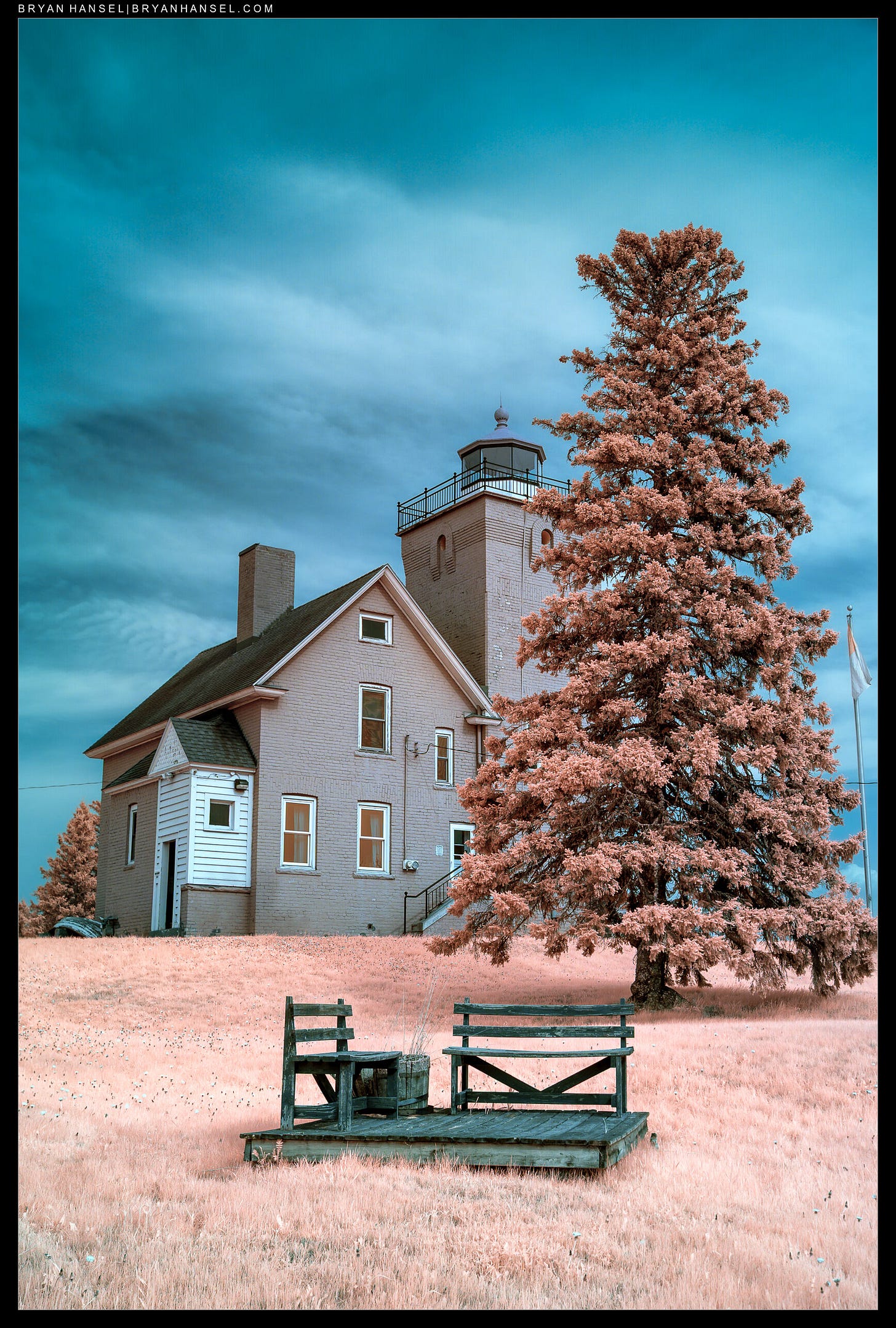 An infrared photo of Two Harbor's lighthouse and a bench in front.