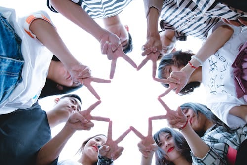 Free A circle of friends forming a star shape with fingers, symbolizing unity and teamwork. Stock Photo