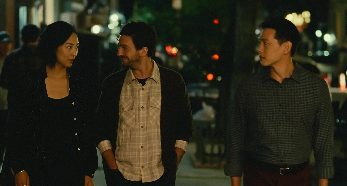 Movie still from Past Lives. A woman and two men walk at night in New York.