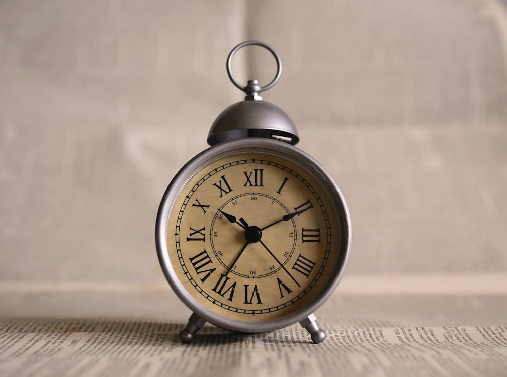 Free Close-up of an antique alarm clock displaying time with classic Roman numerals. Stock Photo