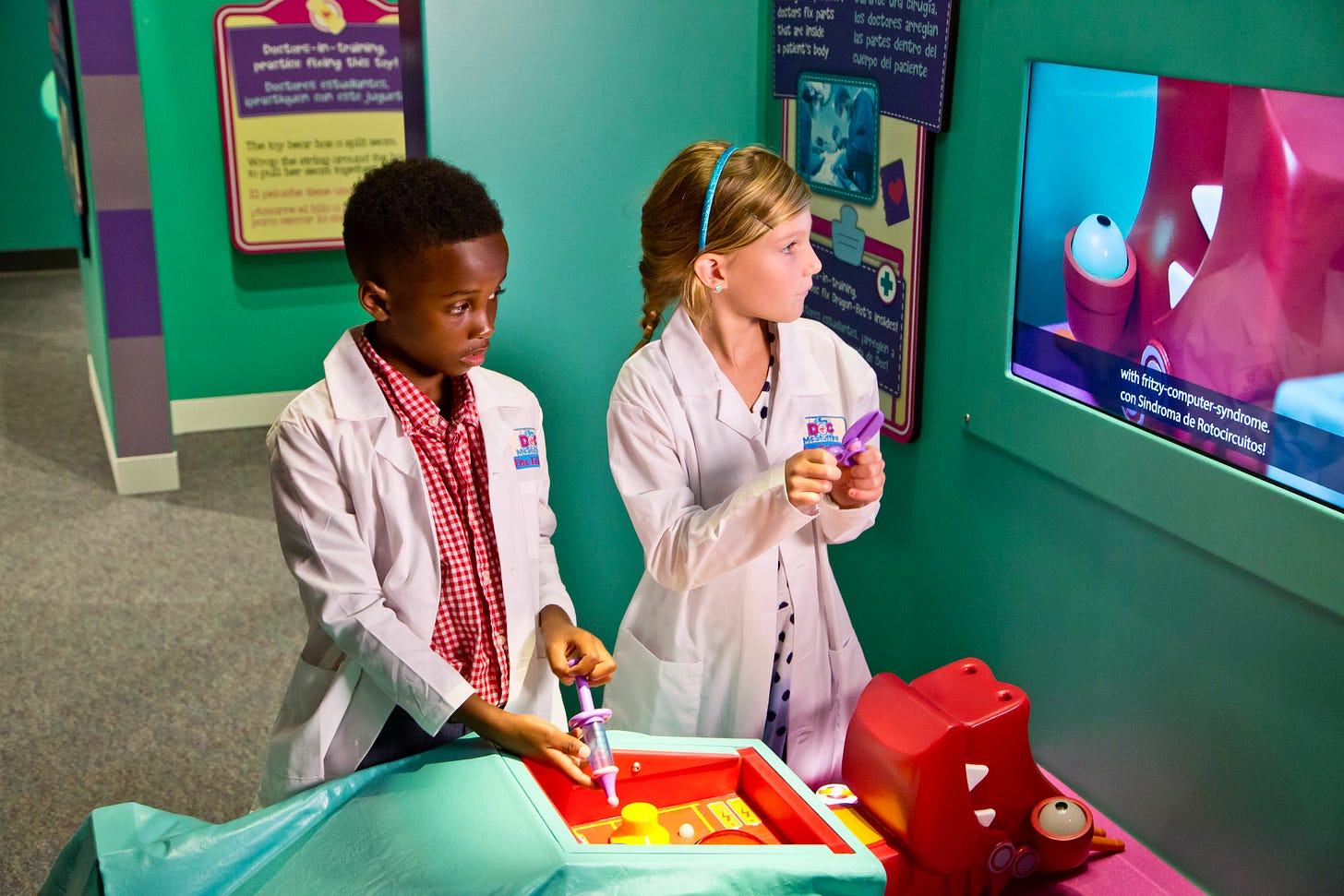 Two children in doctor's coats operate on an ailing robot