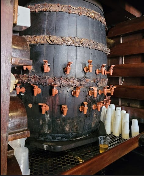 Um barril com várias torneiras daquelas marrons de filtro por onde saem todas as infusões e combinações de cachaça do bar e cachacaria O Cravinho.