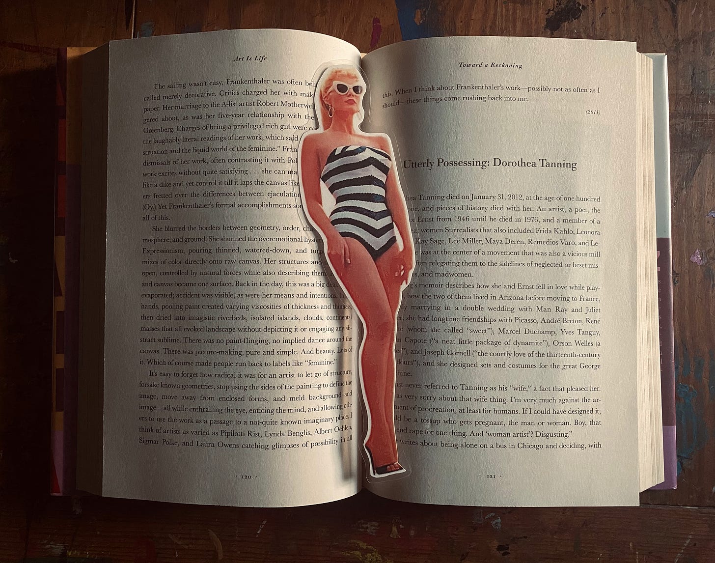 A cutout of Barbie from The Barbie Movie inside the book Art Is Life by Jerry Saltz.