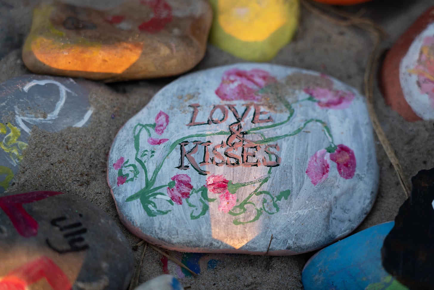 A painted rock with flowers and the words "Love & Kisses" image from Photo by <a href="https://unsplash.com/@jannerboy62?utm_source=unsplash&utm_medium=referral&utm_content=creditCopyText">Nick Fewings</a> on <a href="https://unsplash.com/images/things/kiss?utm_source=unsplash&utm_medium=referral&utm_content=creditCopyText">Unsplash</a>    Part of Driftwood & Grace by Melanie Williams 