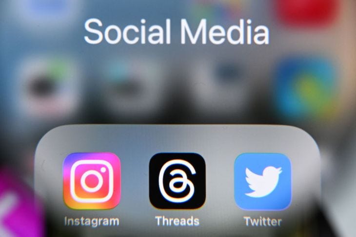 Image of Threads app on iPhone next to Instagram and Twitter