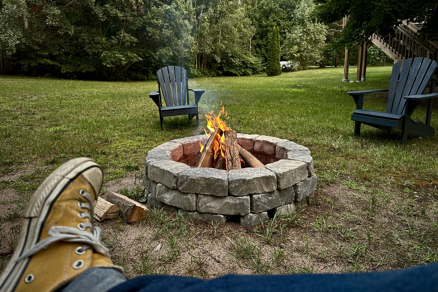 Photo of a fire in a fire pit, surrounded by Muskoka chairs