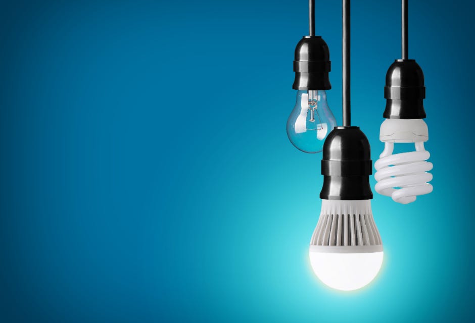 Blue background with three hanging bulbs: one incandescent, one CFL, and one LED