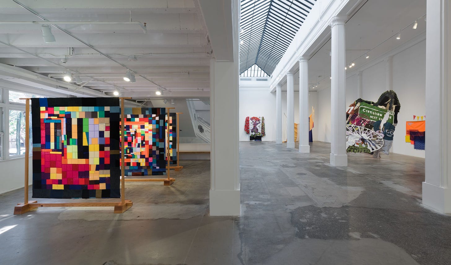 Interior photo of the minimally decorated Hauser & Wirth gallery in Los Angeles during the New Bend exhibition which has colourful, multi-colour quilts on display.