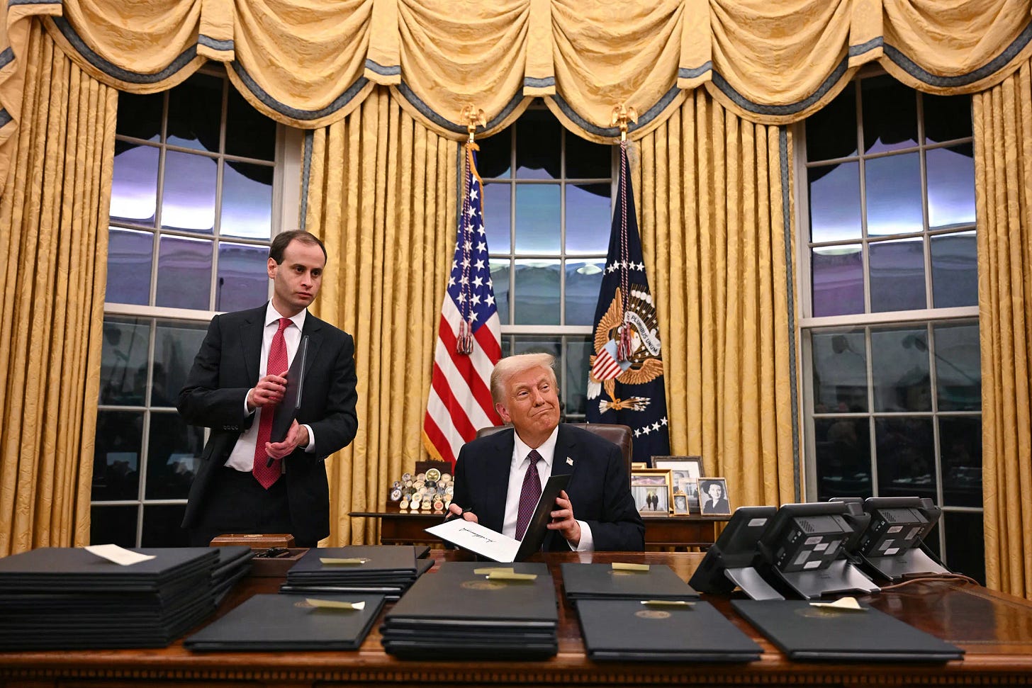 Il presidente Donald Trump firma gli ordini esecutivi nello Studio Ovale della Casa Bianca a Washington, DC, il 20 gennaio.