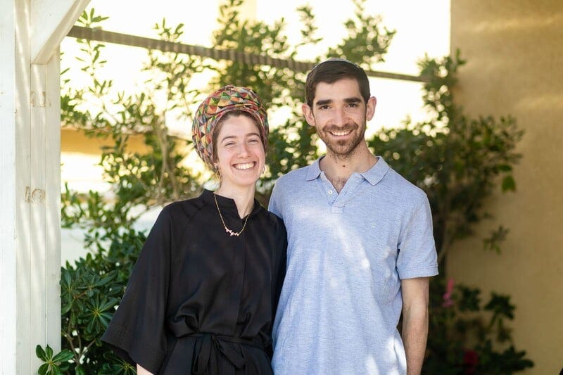 A religiously attired Jewish couple smile for a photo