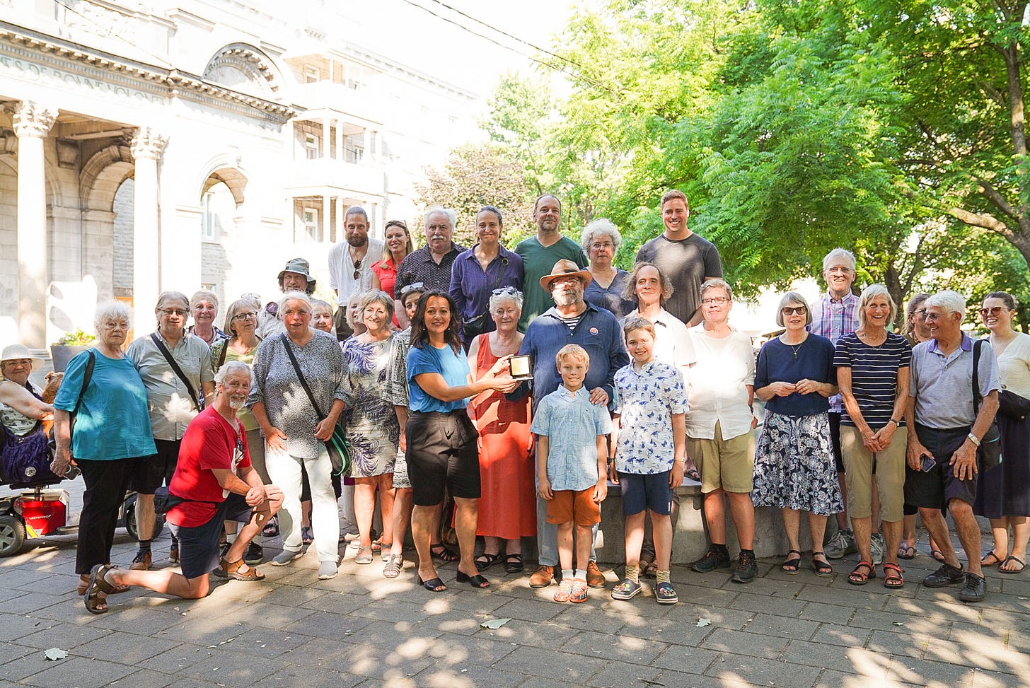 On voit environ 30 personnes qui étaient assemblées au parc Lahaie, sous le soleil, pour la remise de la « Médaille de la députée - Assemblée nationale du Québec » à Bernard Vallée par Ruba Ghazal, députée de Mercier, le 18 juin 2024.