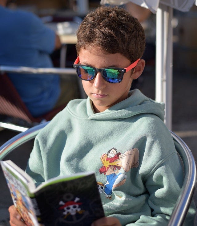 a child with thick sunglasses reading a book