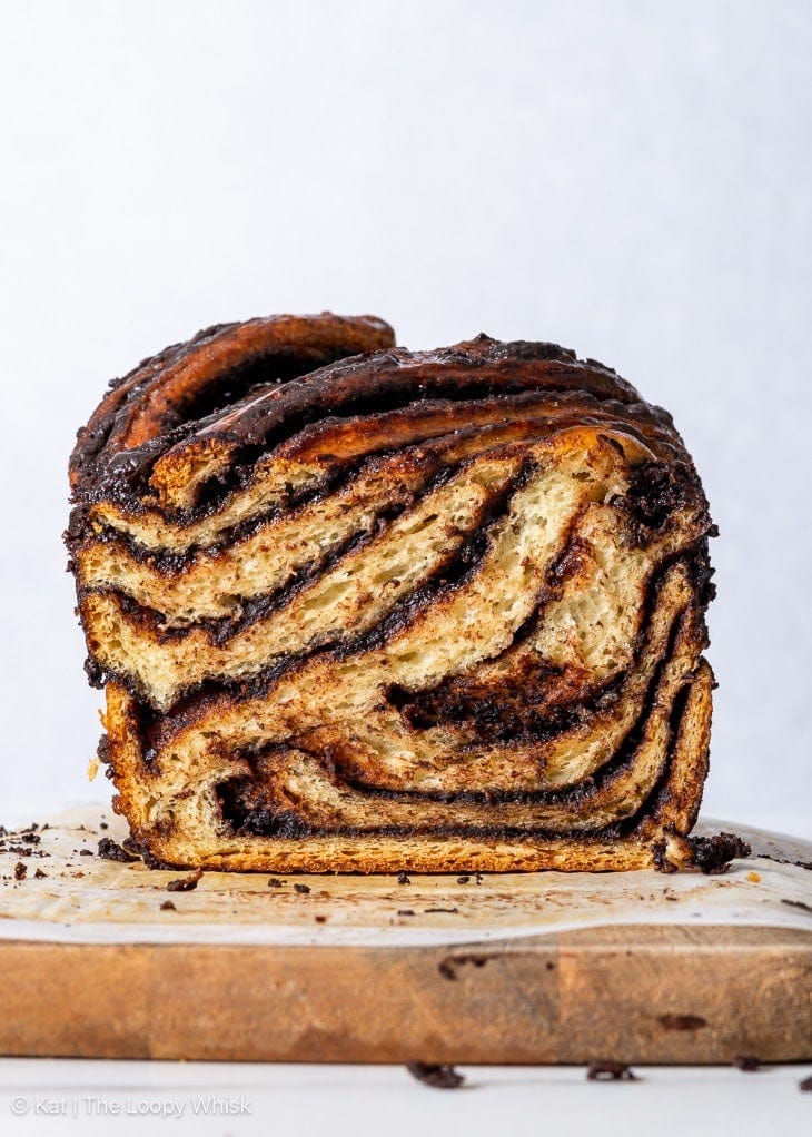 Gluten free chocolate babka on a wooden cutting board with a few slices already cut.