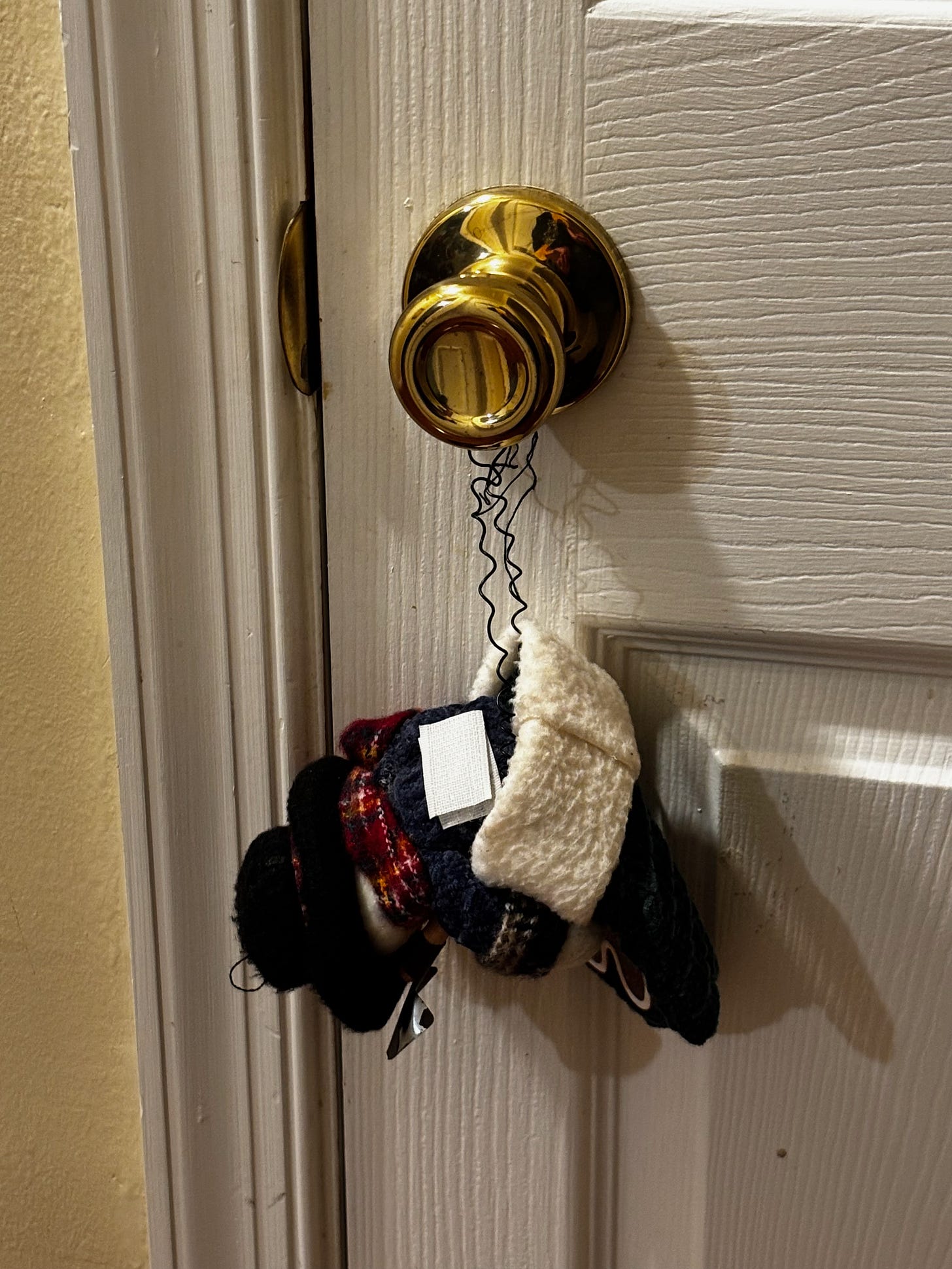 A Christmas decoration that is a snowman in a stocking hanging off of a doorknob