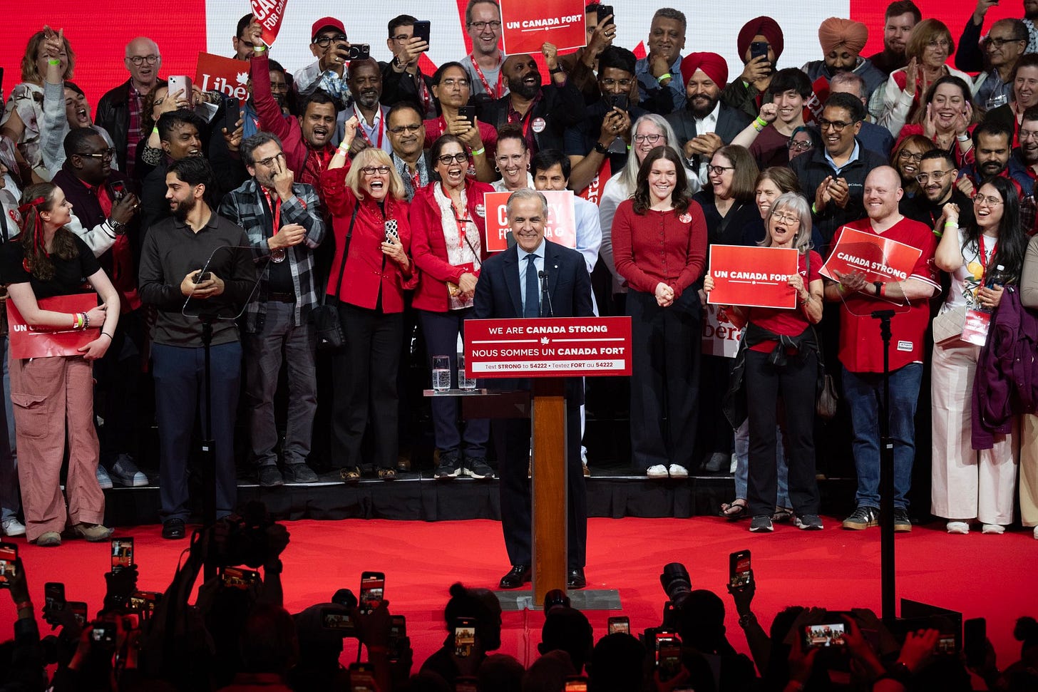 Mark Carney stands on stage with supporters after the results of the Canadian federal election are called.