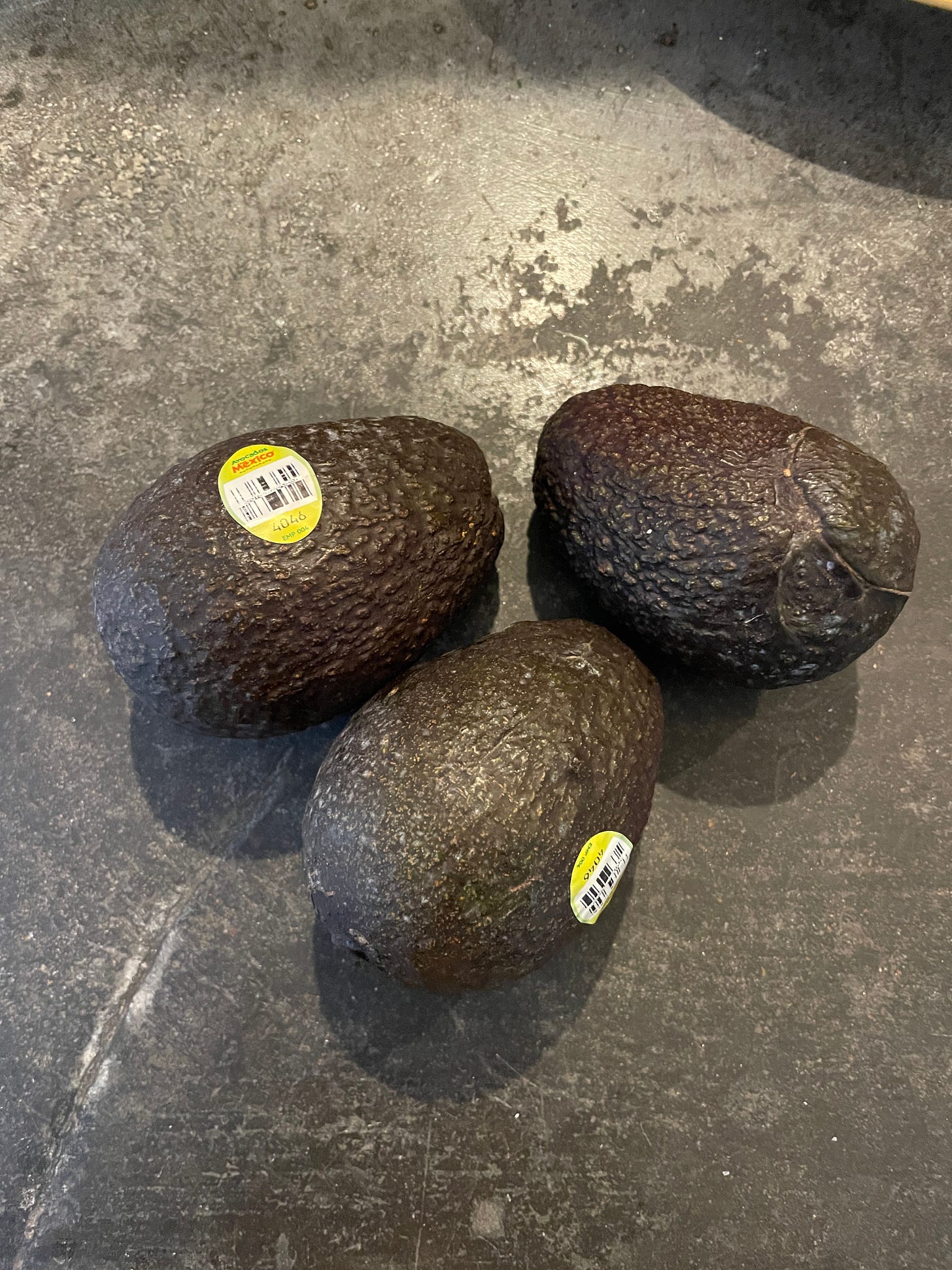 three avocados on a counter