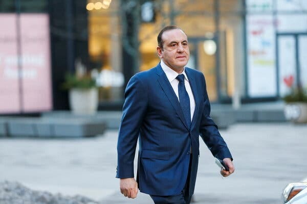 Gamal Abdelaziz walking down a street, wearing a blue suit, white shirt and blue tie.