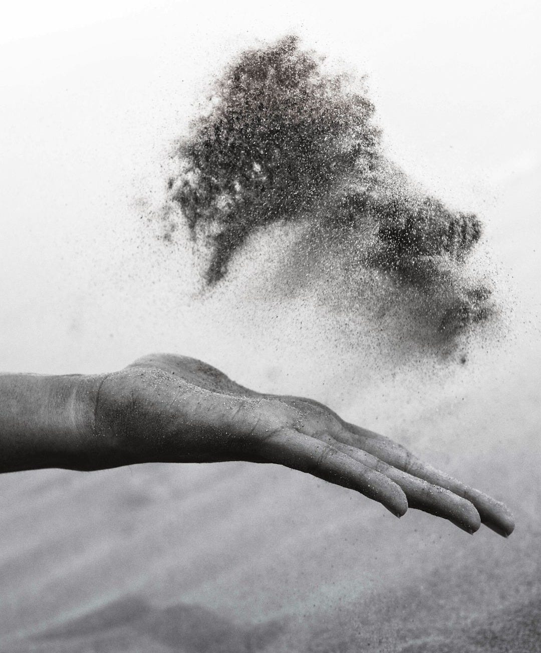 grayscaled photography of person's hand spreading sand grayscaled photography of person's hand spreading sand