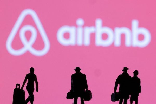 Figurines-are-seen-in-front-of-displayed-Airbnb-logo