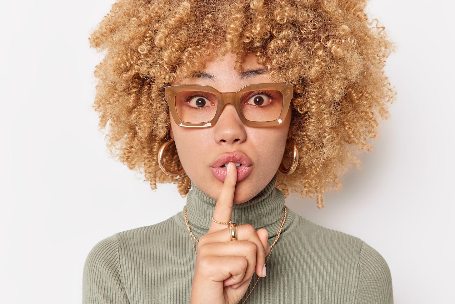 Pretty young mixed race woman, wild curly hair pressing a finger to her lips. Shh.