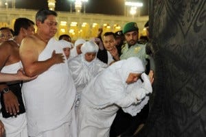 A Hajj pilgrim touches and prostrates towards the Black Stone at the corner of the Ka'bah.