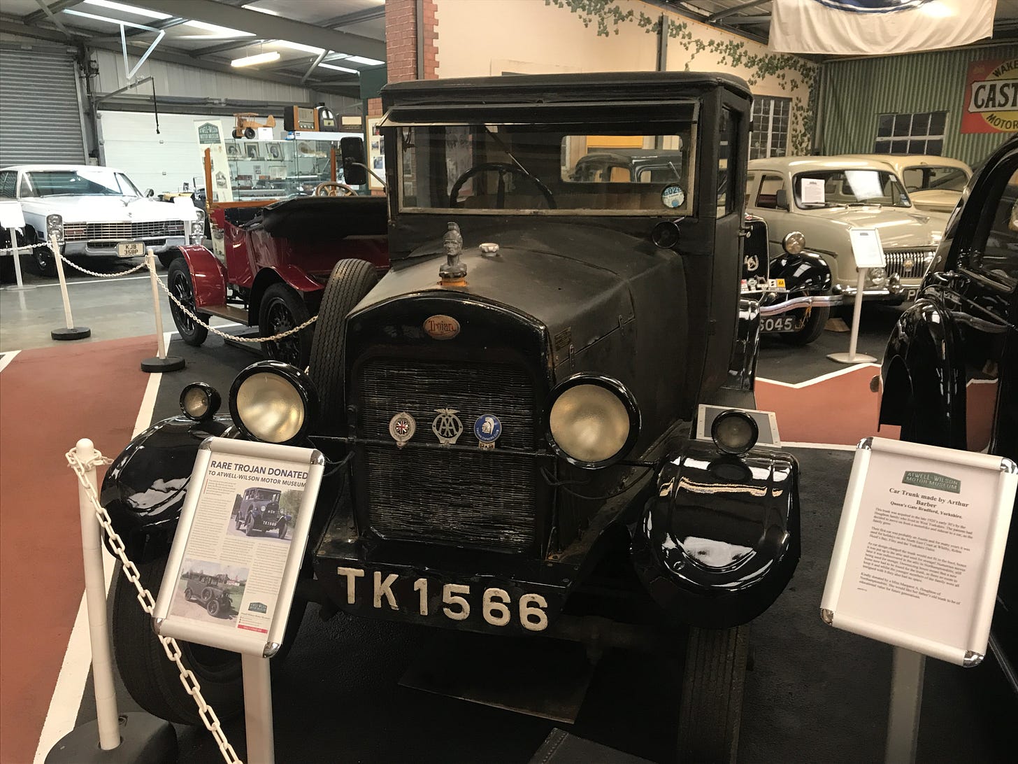 A rare Trojan vintage car at the Atwell Wilson Motor Museum, Stockley Lane, Calne, Wiltshire. Here we see the car on display with information boards in the foreground telling visitors about the car’s history. The registration plate of the vehicle is TK1566. In the background, we can see a few of the other vehicles in the collection. 