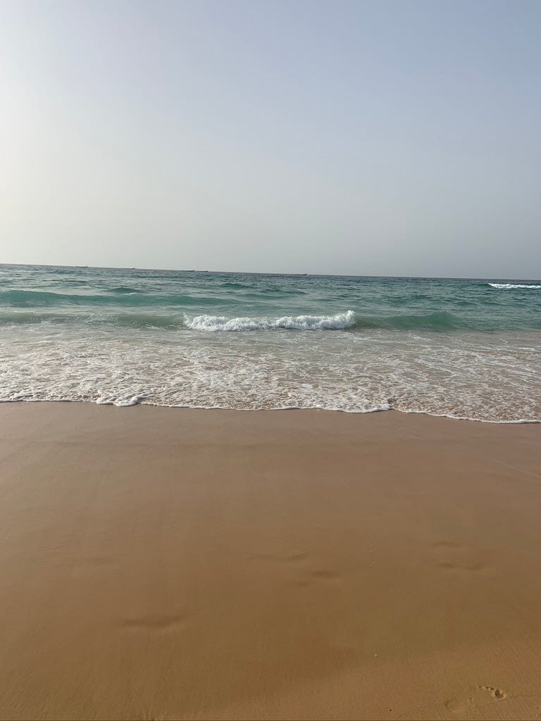 A photo of a beach in Dakar Senegal with light blue water on a clear day