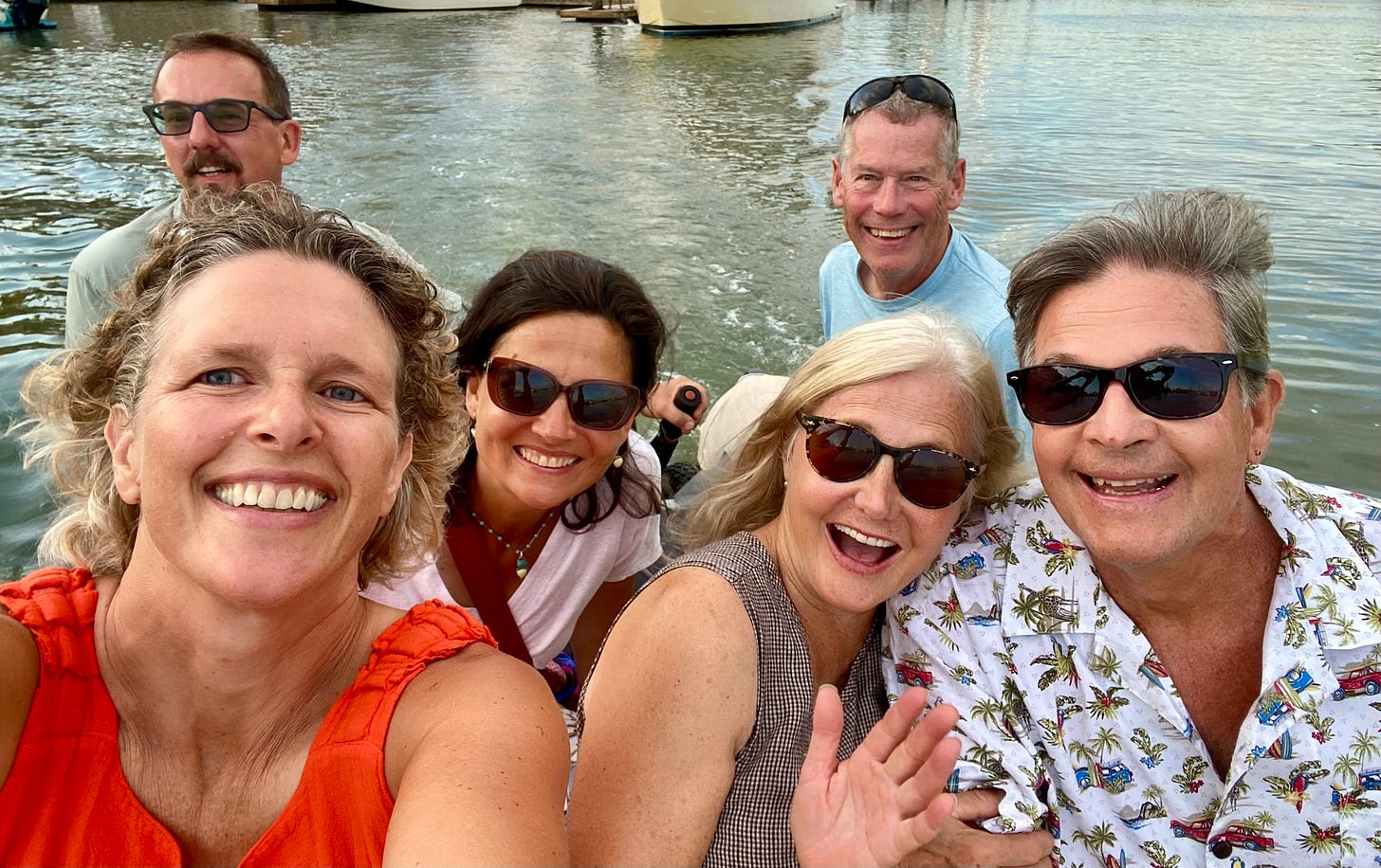 Three men and three women take a selfie while in a dinghy in a marina