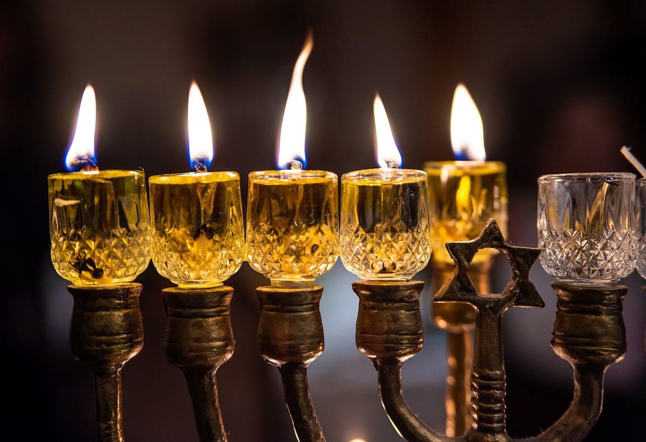 a glass hanukkah menorah with four candles lit