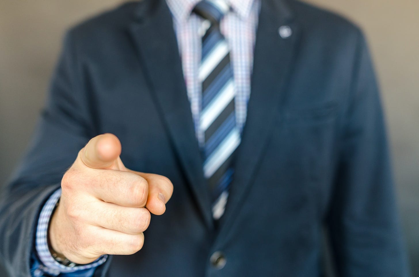 Man Wearing A Suit Jacket And Stripe Necktie Point Towards You