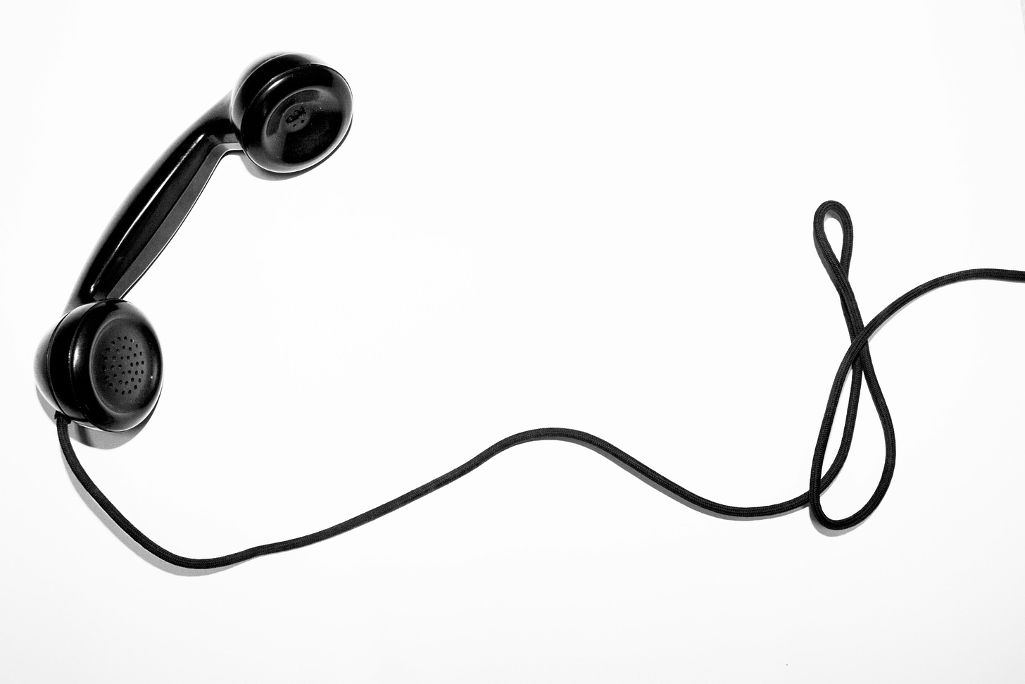 Black phone headset with winding cord on white background
