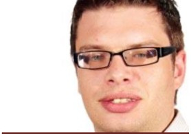 A person wearing glasses and smiling

Description automatically generated