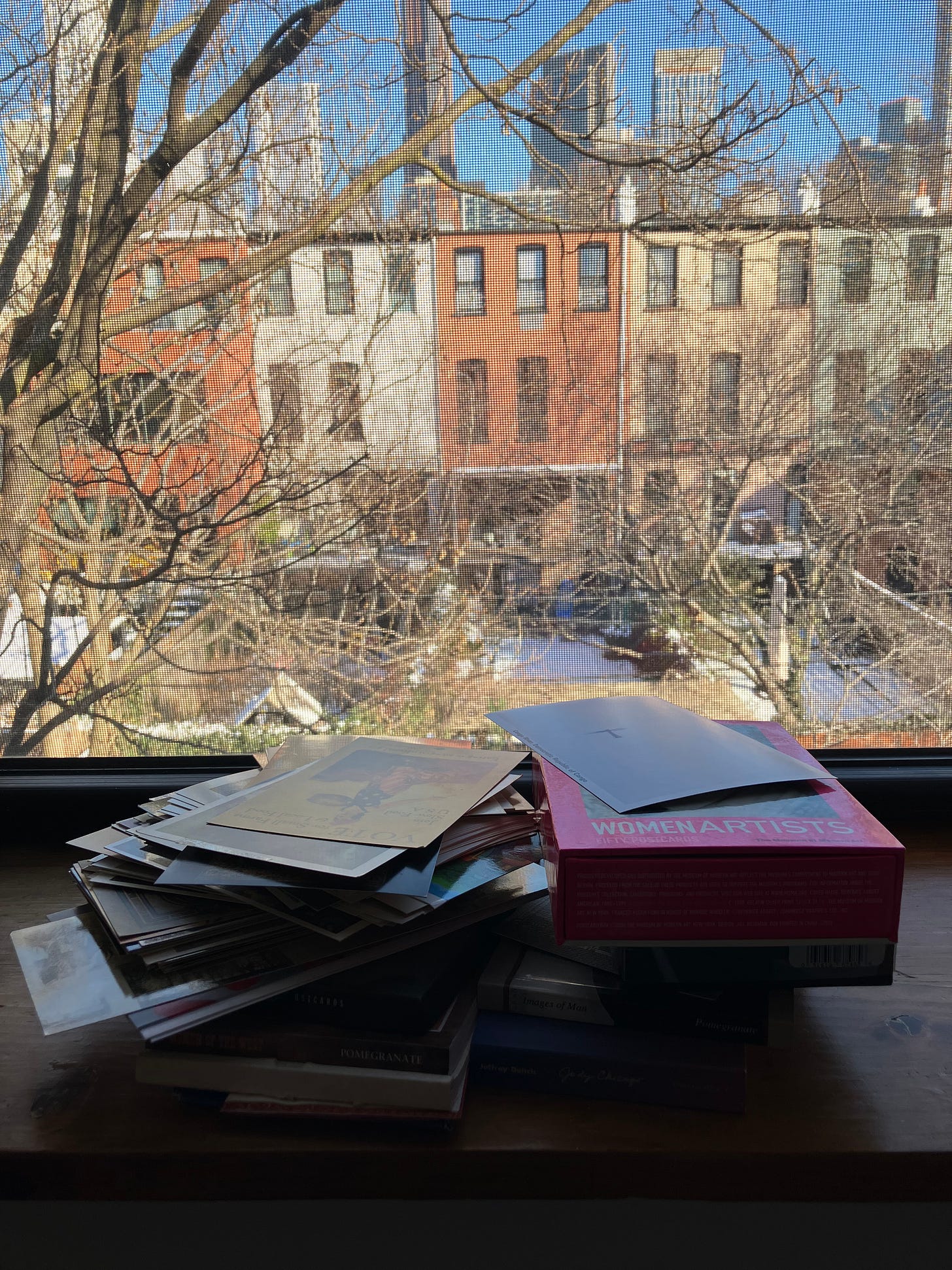 pile of postcards stacked on windowsill overlooking backyard