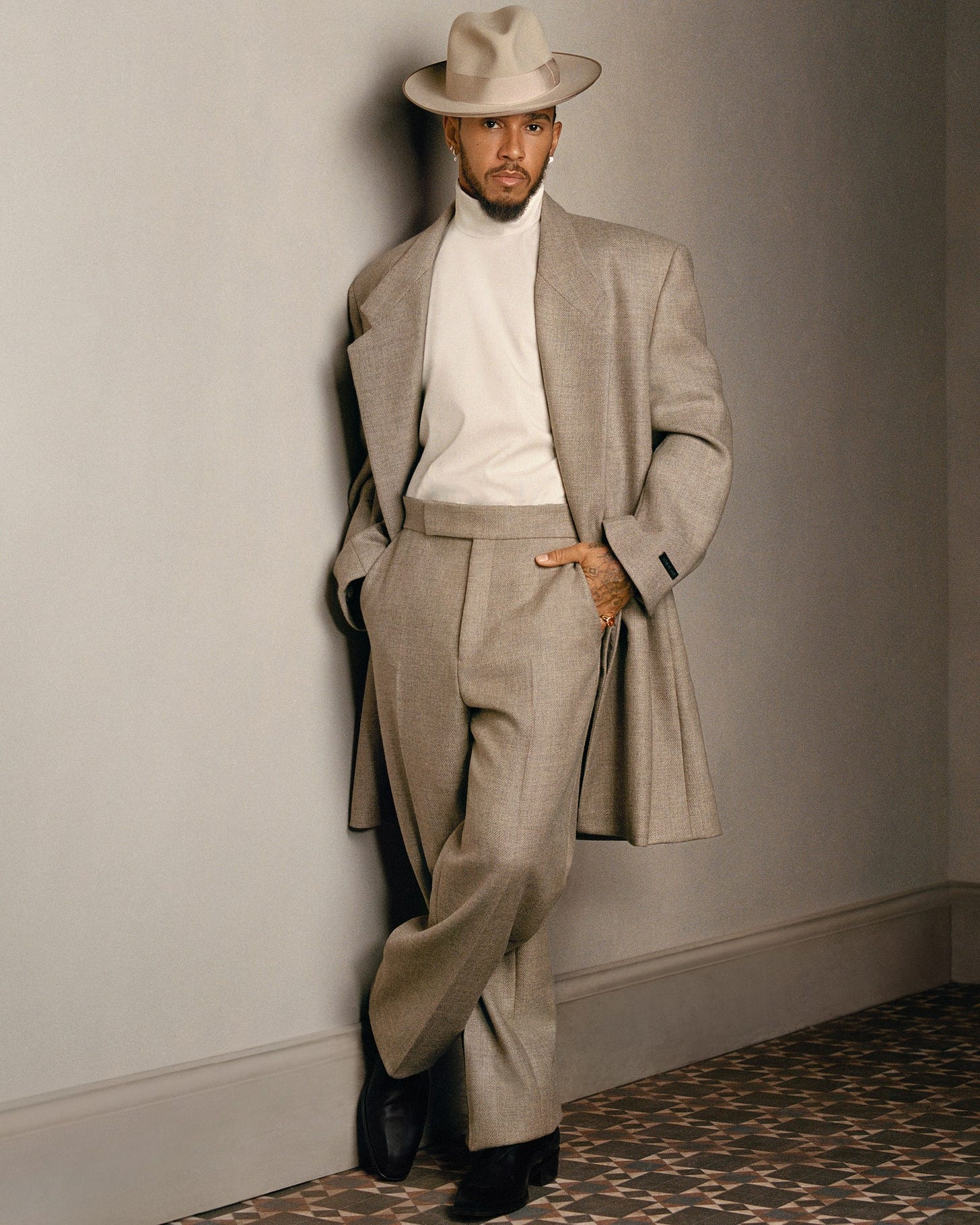 Image may contain Lewis Hamilton Clothing Formal Wear Suit Coat Hat Jacket Adult Person and Blazer