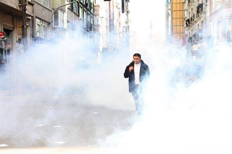 photograph of a man walking inside a cloud of tear gas as he smokes a cigarette