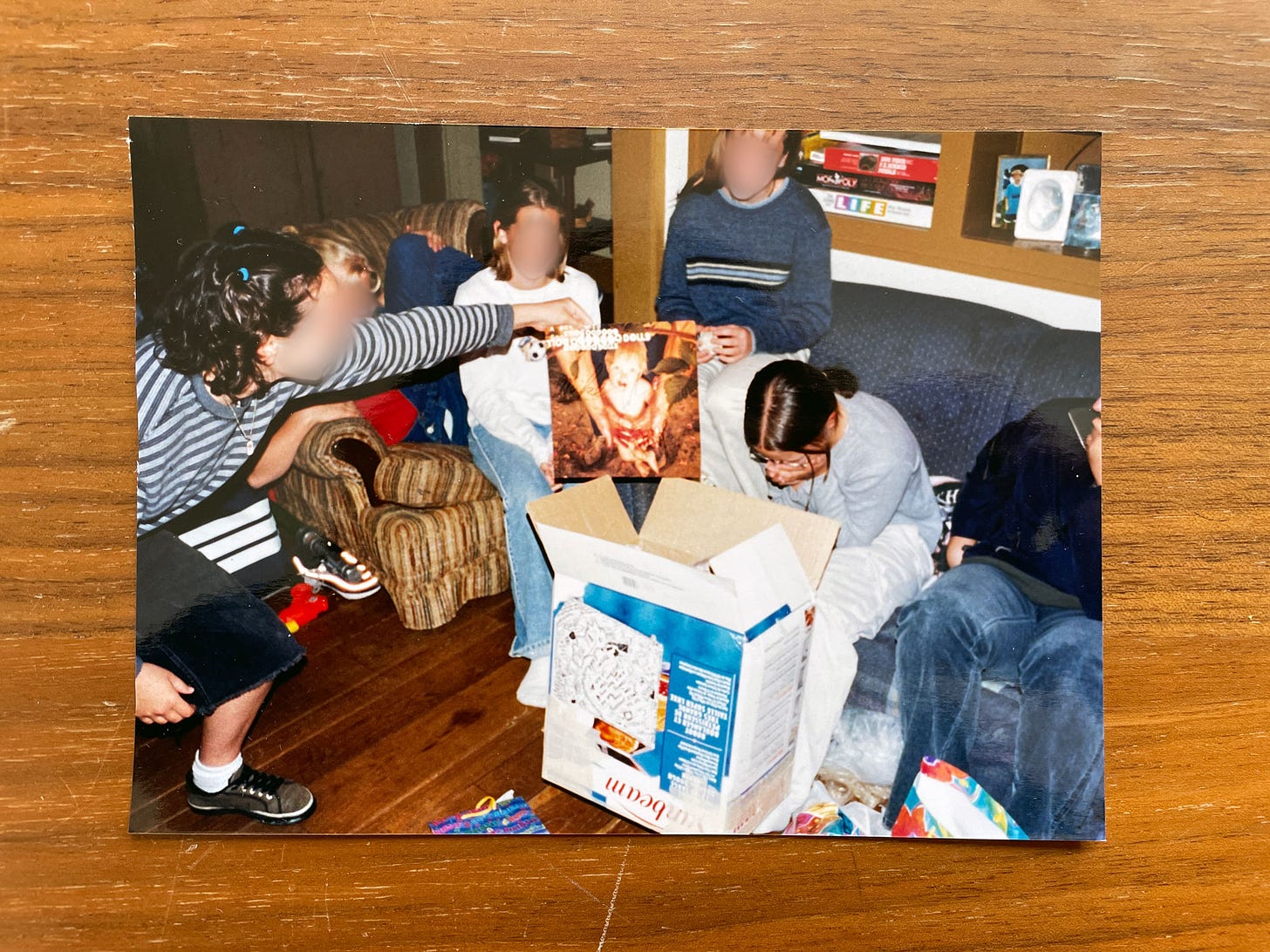 6 people sitting in a living room around a breadmaker box, one person is crying, one person is holding an autograph from the Goo Goo Dolls