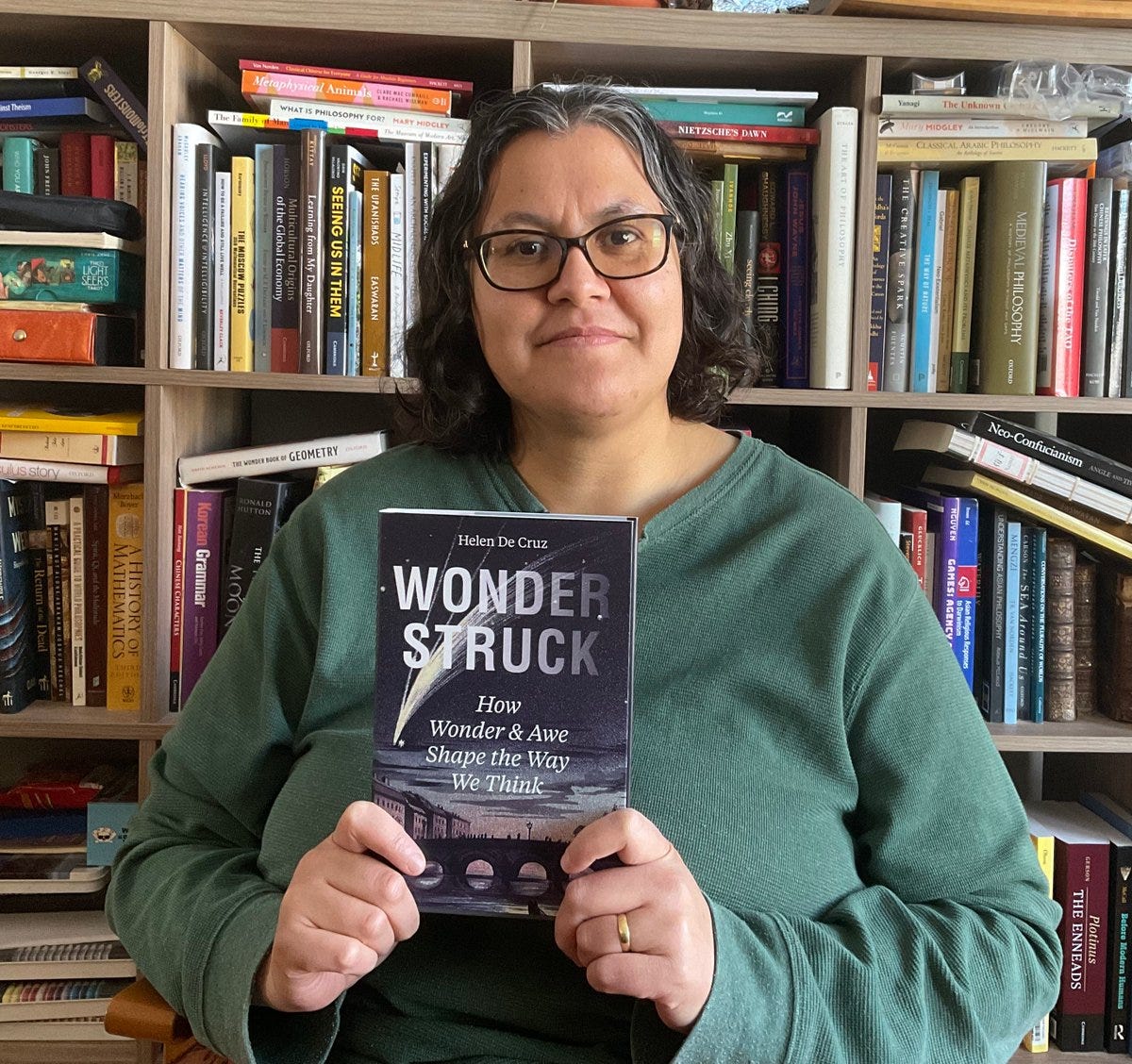 Me sitting in front of many books, holding the book Wonderstruck