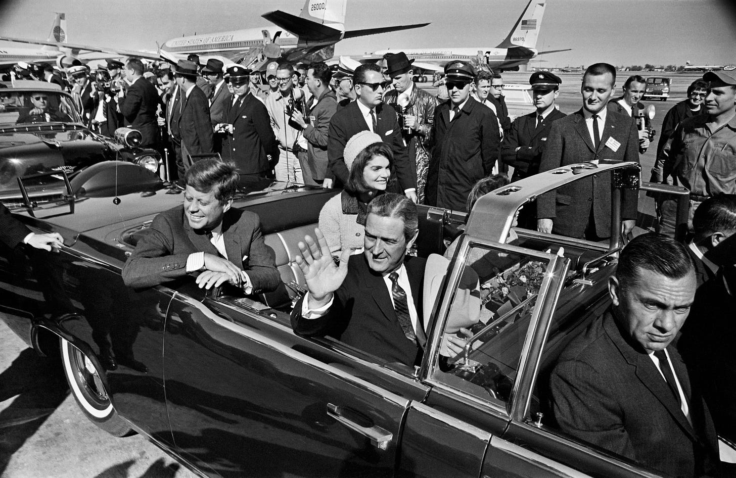 Texas Gov. John B. Connally Jr. waves to the crowd at Love Field as the Kennedys leave for a 10-mile tour of Dallas. The president asked about the weather earlier in the day and opted not to have a top on the limousine. 