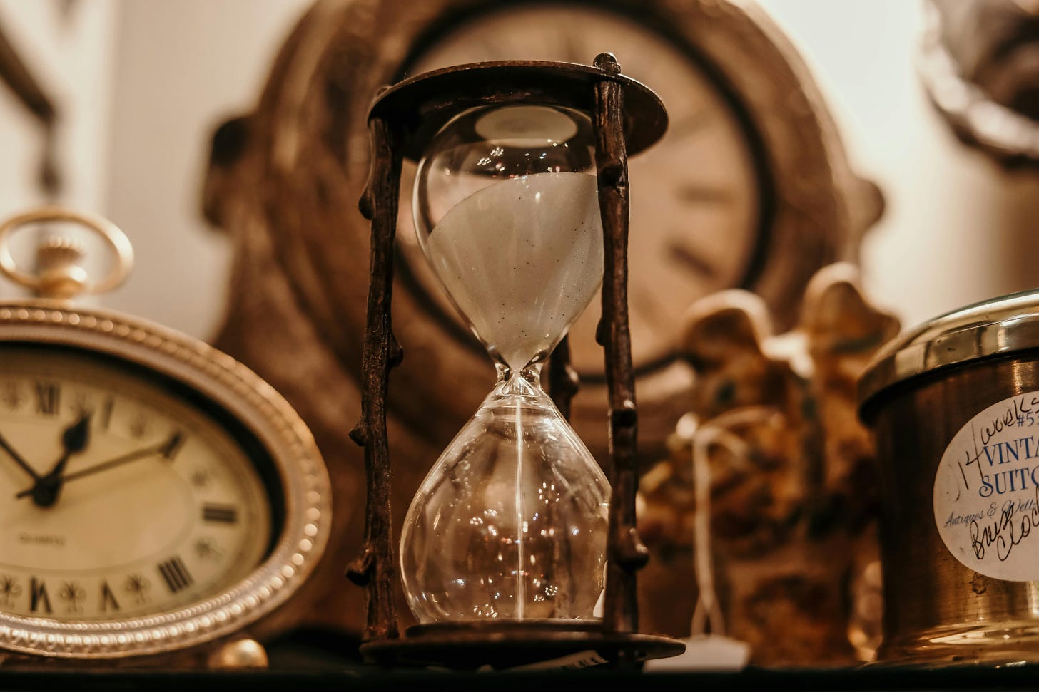 Several gold clocks and an hour glass sit on a table.