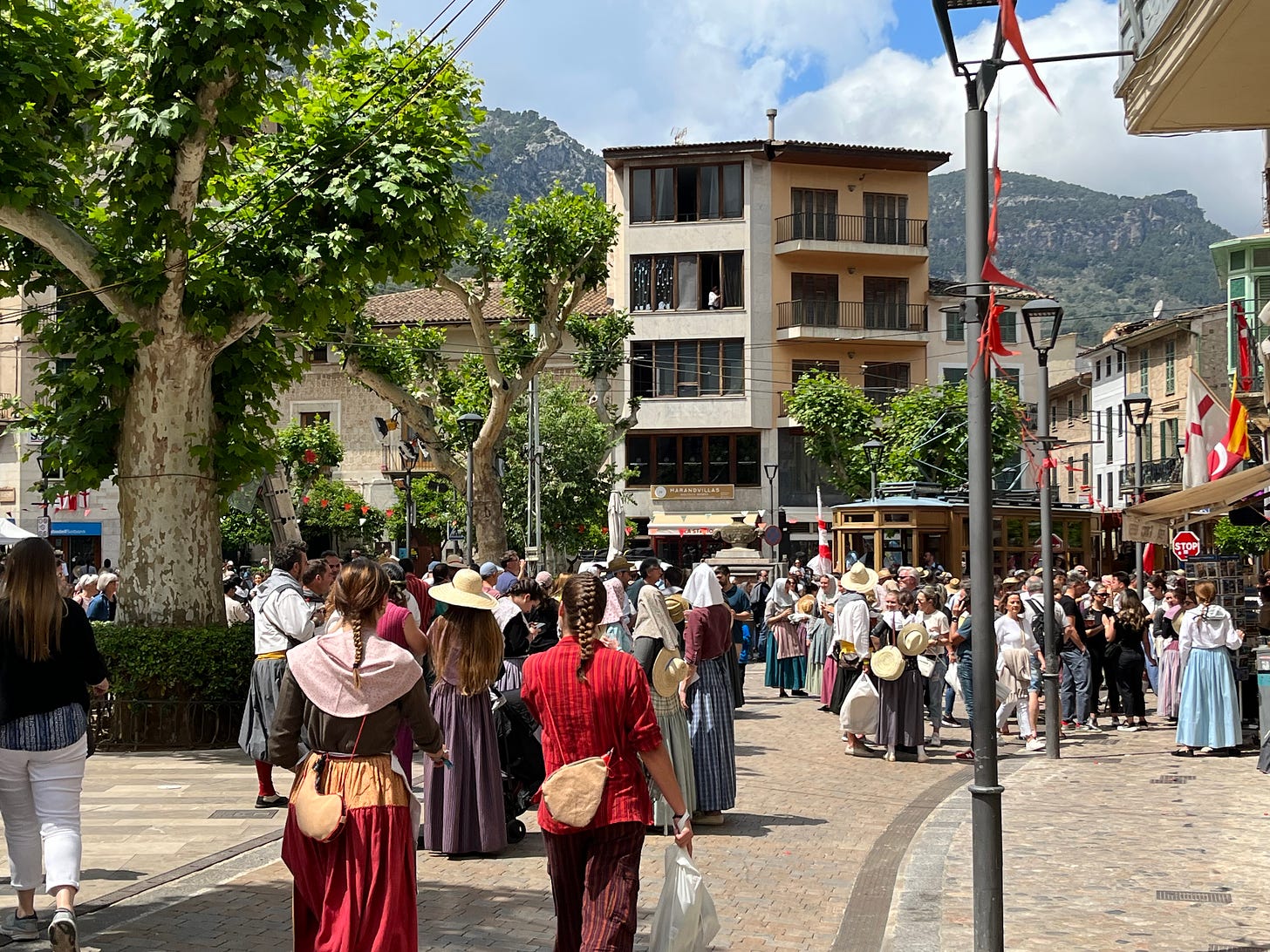A corner of the main square in Soller, filled with people in traditional period costumes