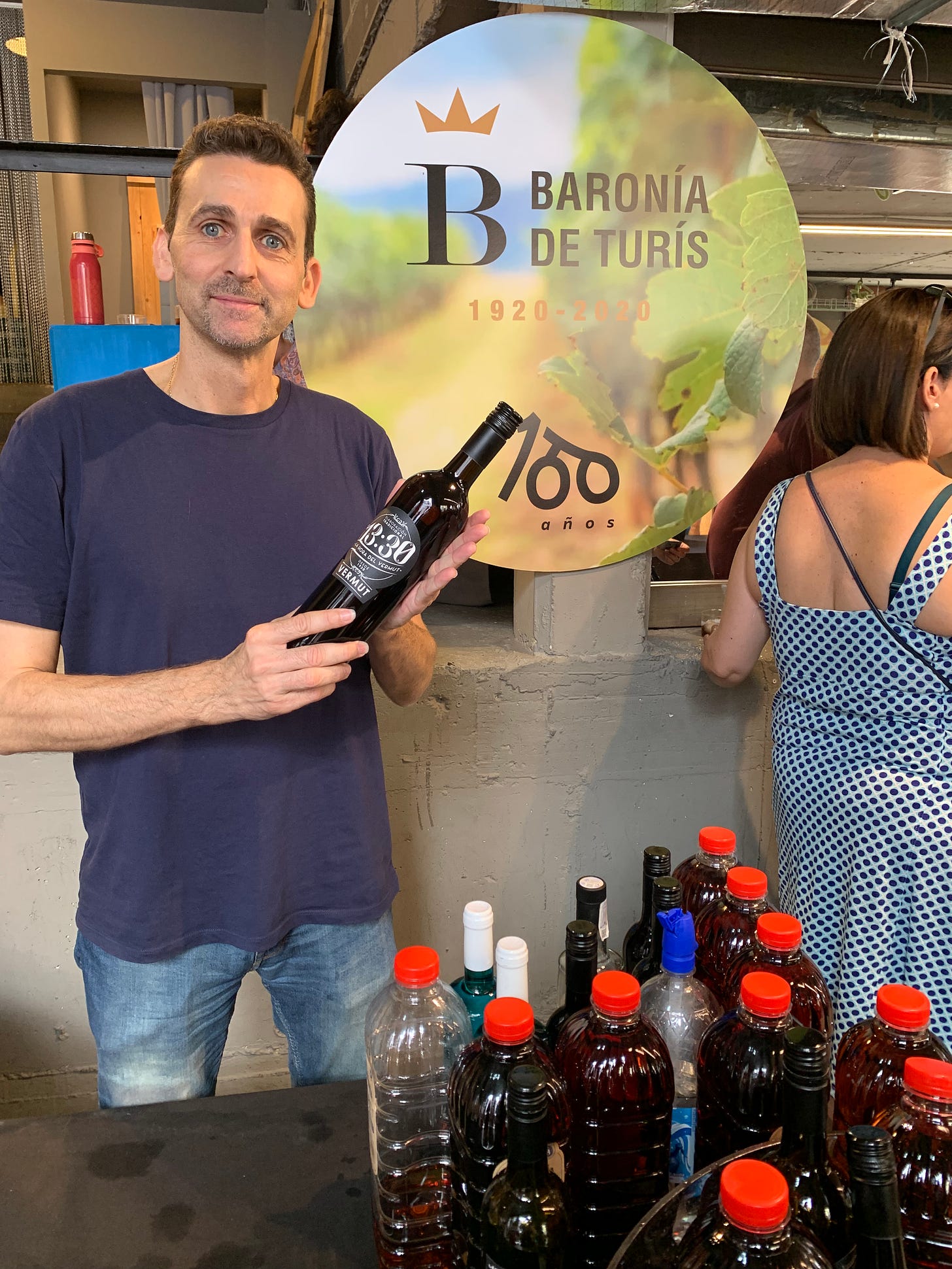 A vendor from Baronía de Turís holds a bottle of vermut.