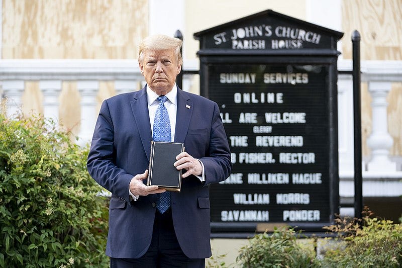 Trump, wearing a blue suit and holding a bible upside down, standing in front of St. John's Church.