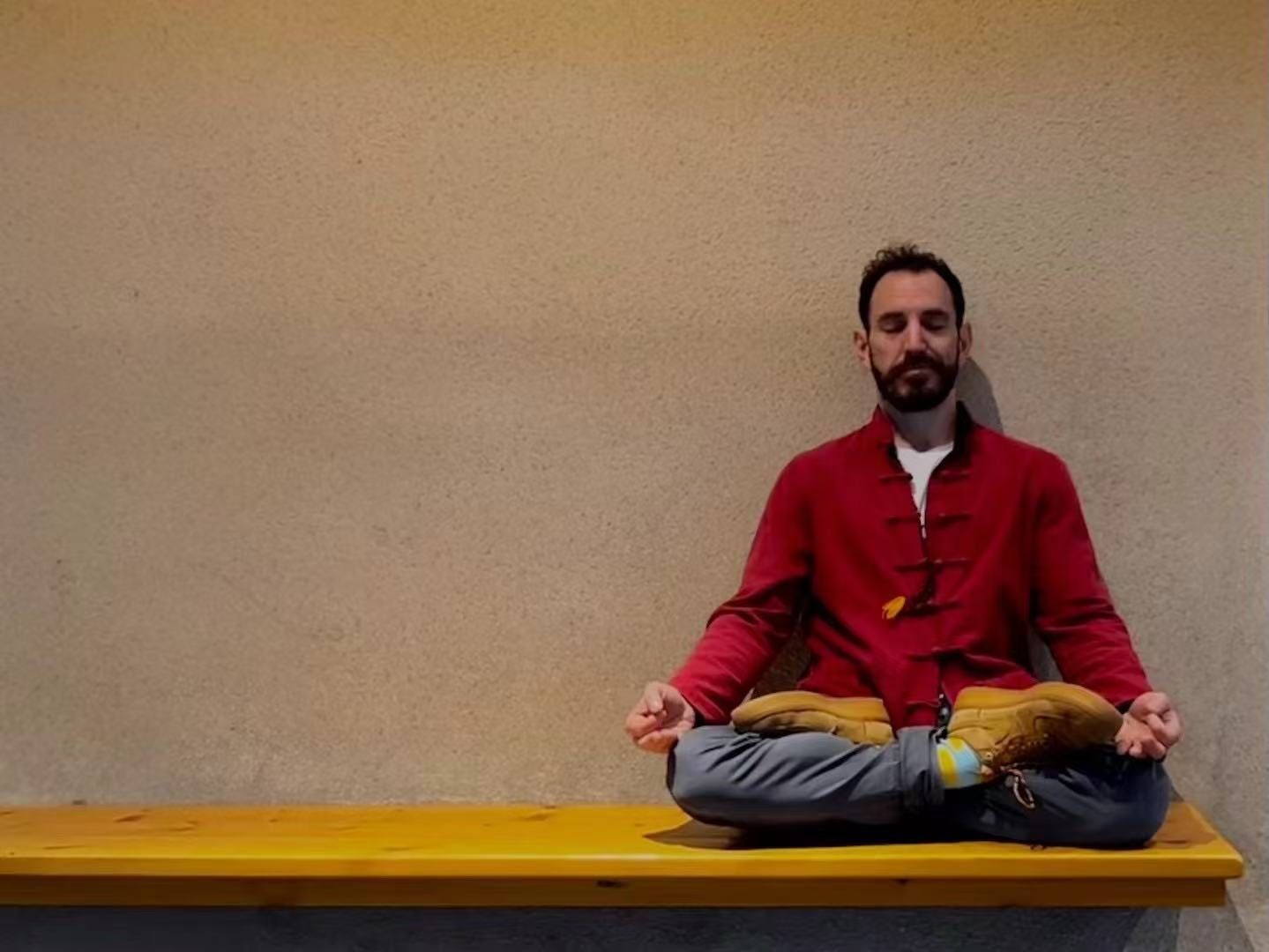 Man meditating in lotus position in front of concrete wall