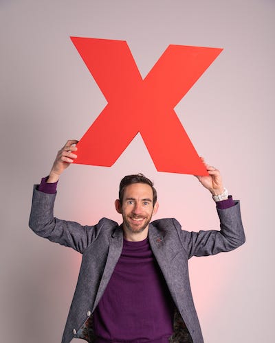 Rob Baker holding a giant "X" overhead