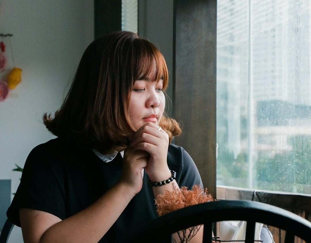 woman sitting near clear glass window