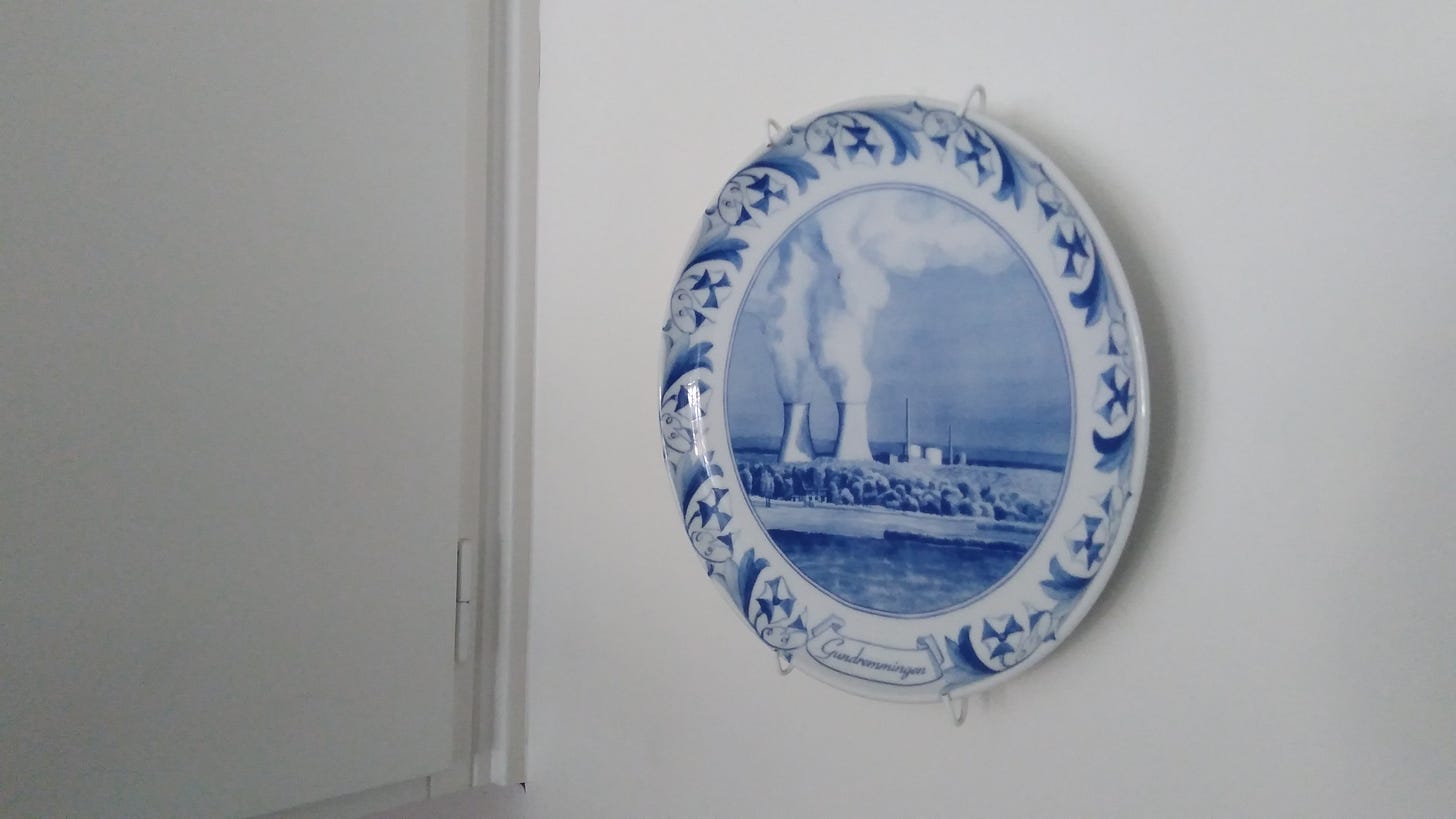 Blue & white china plate with reactor chimneys in a landscape hanging on a white kitchen wall