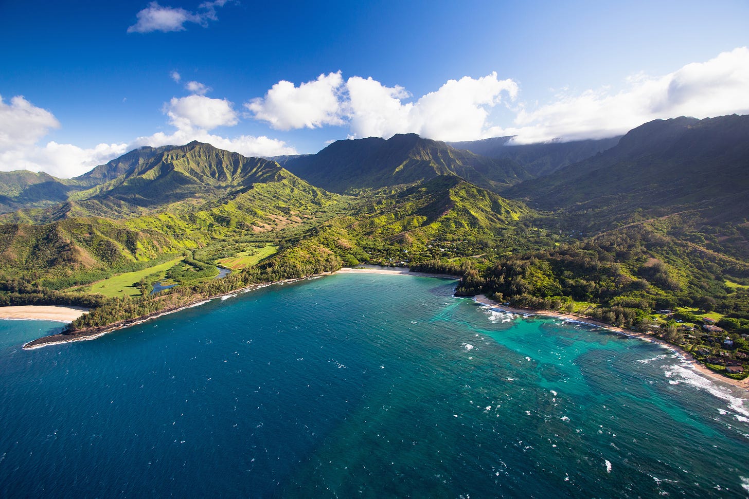 A picture of a blue water bay surrounded by lush green mountains in Hawaii