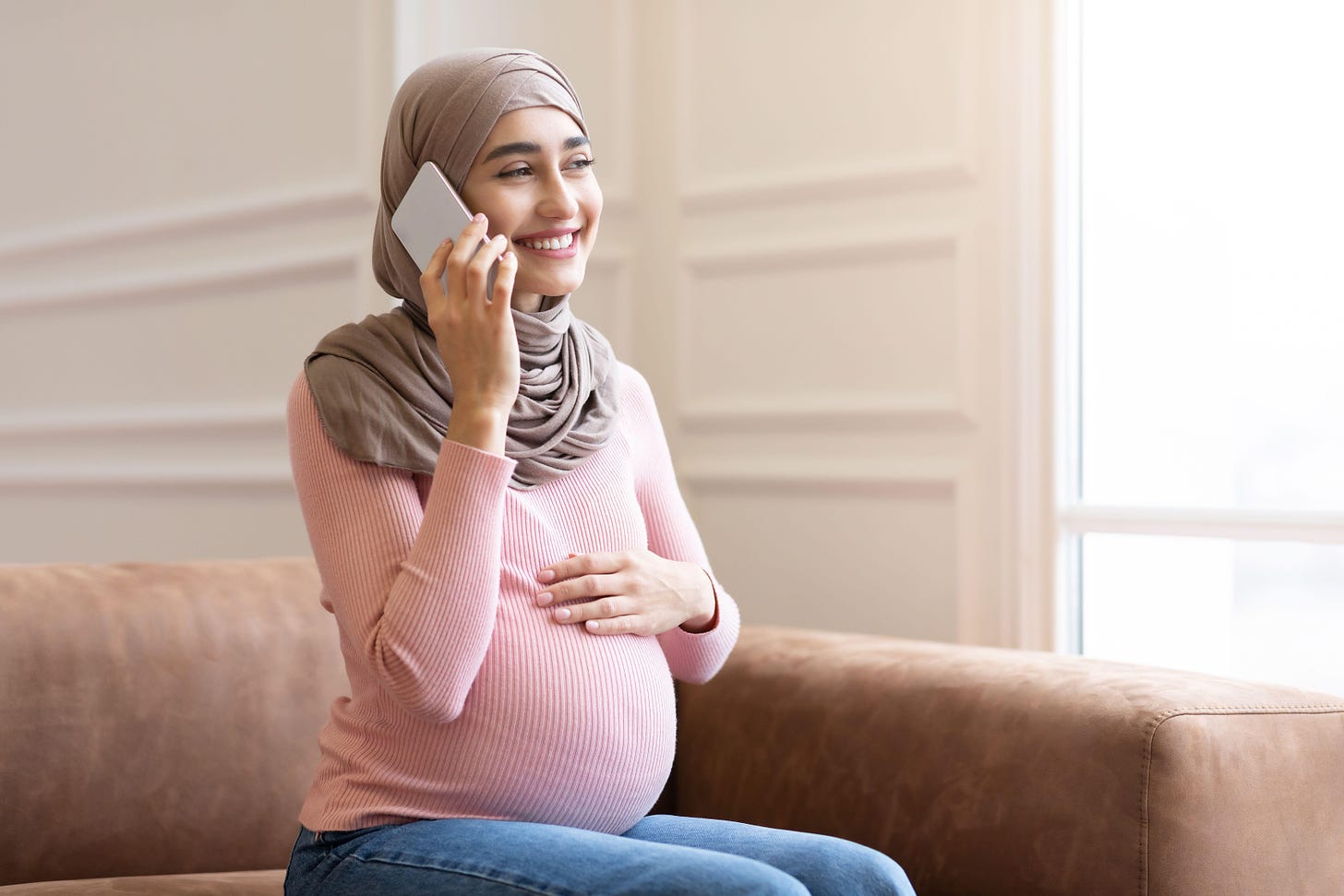 A young pregnant Muslim woman talking on the phone