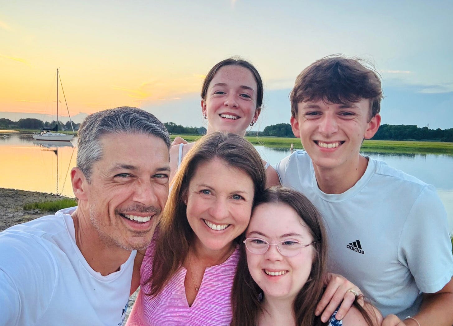 photo of Peter, Amy Julia, Marilee, Penny, and William posing for a selfie in front of a sunset over water