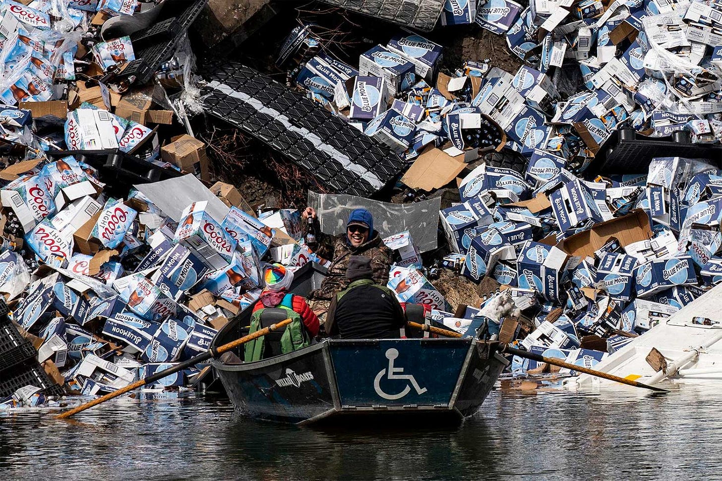 A group of anglers claim a bottle of Coors Light from a derailed railcar on the banks of a river.